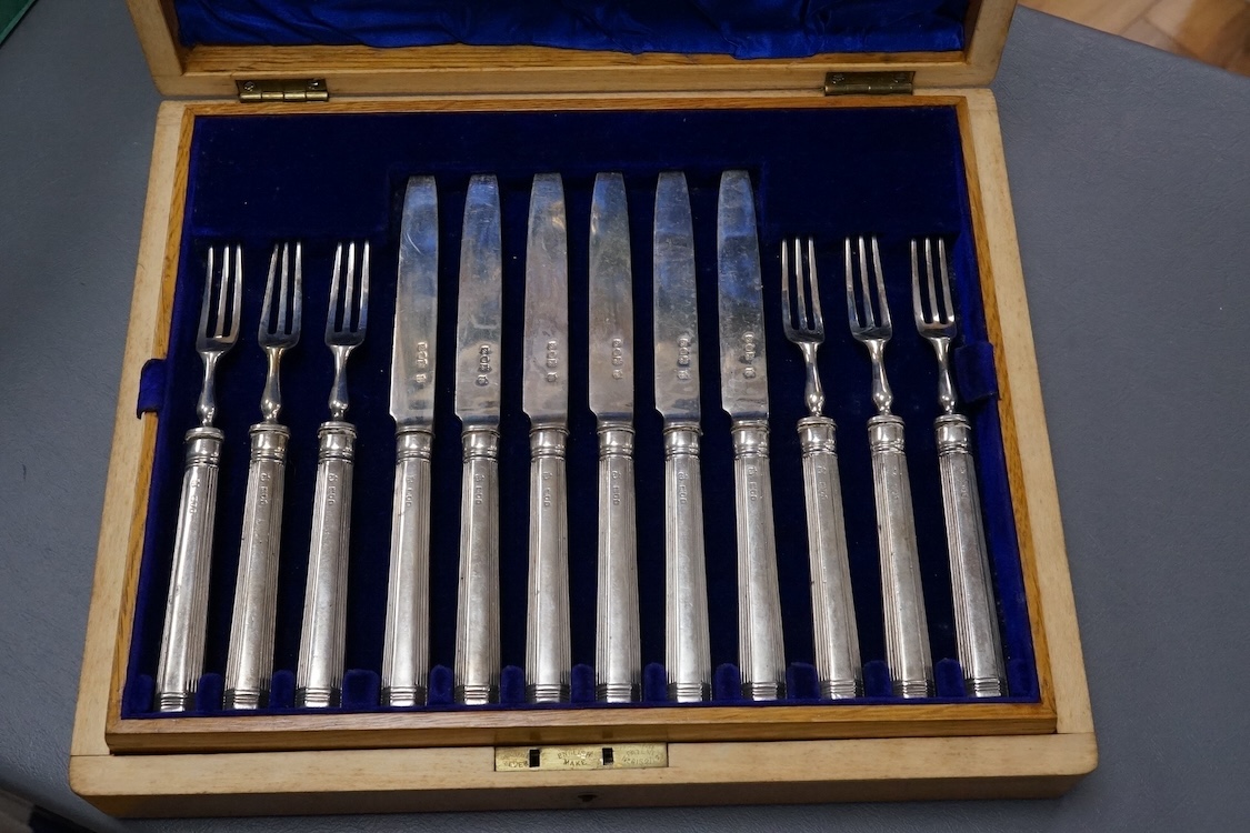 A set of twelve pairs of silver dessert eaters, by Thomas Bradbury & Sons, London, 1913, knife 19.8cm, handles loaded, housed in a fitted oak canteen.
